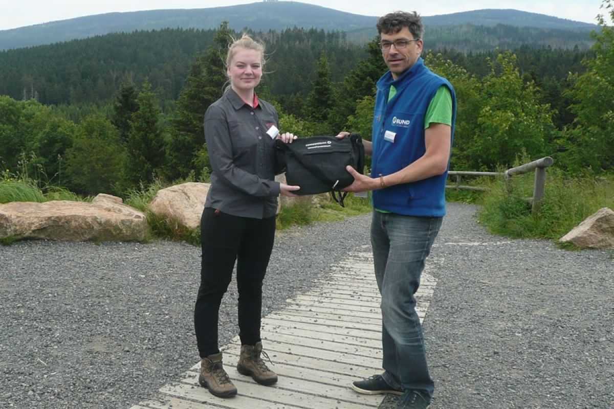 Tessa Nähring erhält ihre Grundausrüstung – eine Umweltbildungstasche der Commerzbank – aus den Händen ihres Betreuers Dr. Hermanns Martens vom Nationalpark-Besucherzentrum TorfHaus.